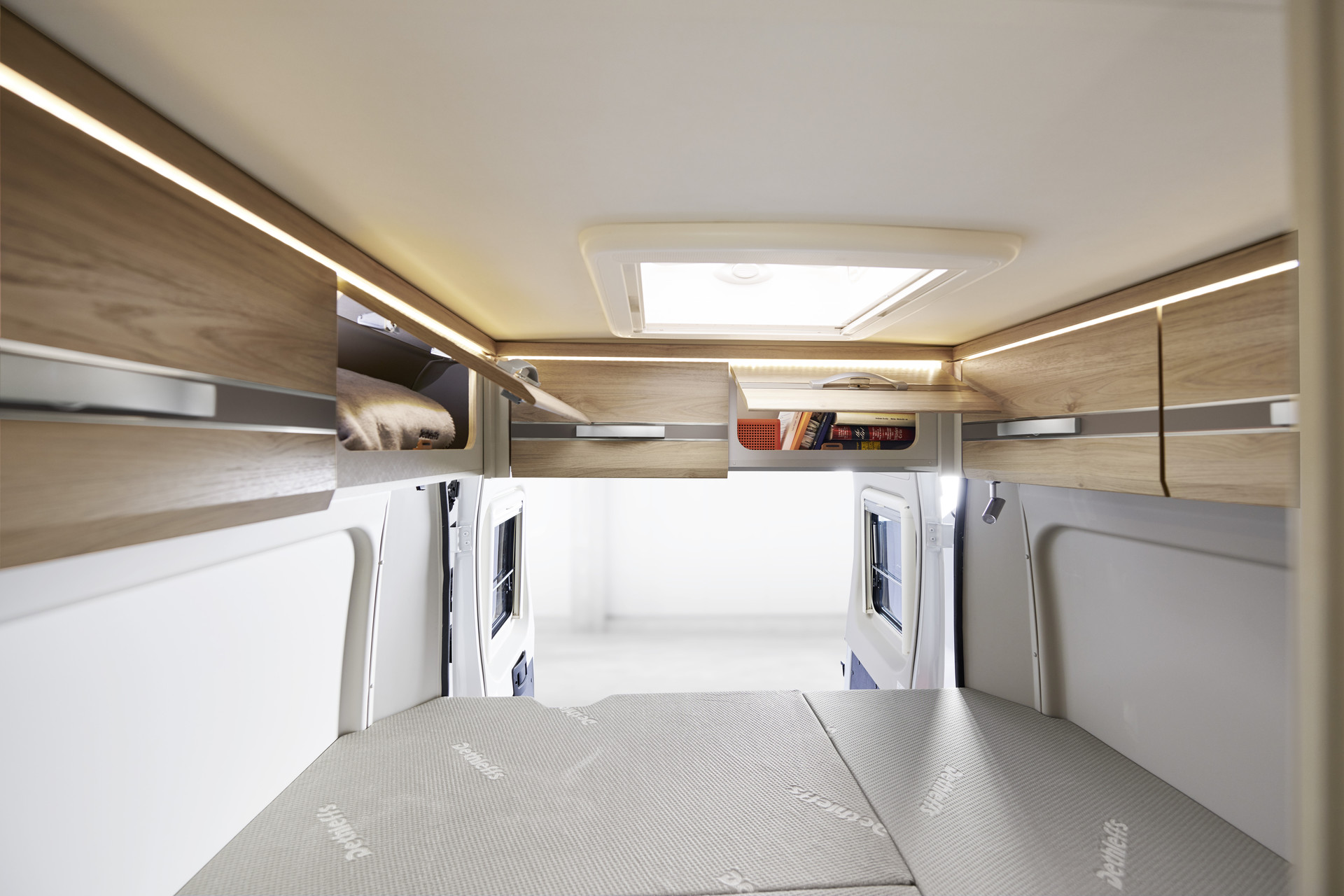 Os armários suspensos de série acima da porta traseira fornecem espaço de arrumação adicional e têm iluminação indireta.