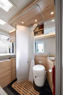 Utilização perfeita do espaço graças à porta do duche giratória em vidro fosco com base de duche por baixo da cama traseira.